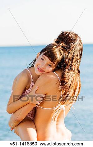 Happy mother carrying her daughter at the beach and looking at camera View Large Photo Image Stock Image - Happy mother carrying her daughter at the beach and looking at camera. Fotosearch
