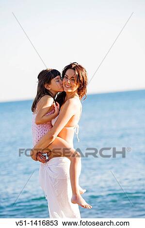 Happy mother carrying her daughter at the beach View Large Photo Image Stock Image - Happy mother carrying her daughter at the beach. Fotosearch