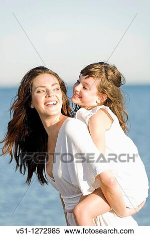 Happy mother carrying her daughter at the beach View Large Photo Image Stock Photography - Happy mother carrying her daughter at the beach. Fotosearch