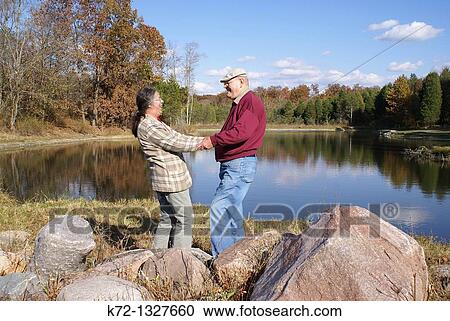 Happy older couple laughing by a lake View Large Photo Image Stock Image - Happy older couple laughing by a lake. Fotosearch