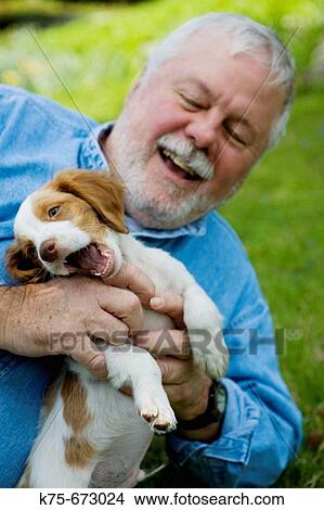 Picture - Happy senior with his new puppy. Fotosearch