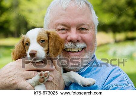 Stock Photography - Happy senior with his new puppy. Fotosearch