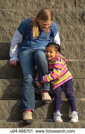 Stock Image - Happy sisters [Caucasian and Latina] from ethnically mixed family. Fotosearch