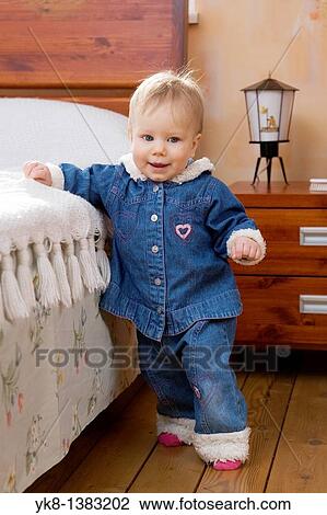 Stock Image - Happy Smiling Ten Month Old Baby Walking First Steps by Bed. Fotosearch