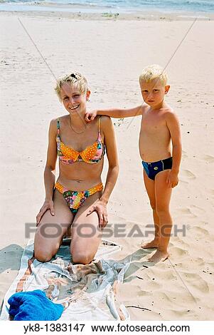Stock Photo - Happy smiling young woman with kid boy on beach. Fotosearch