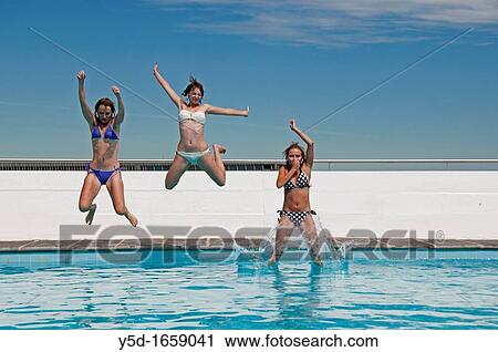 Stock Image - happy summertime, three young women jumping to swimming pool. Fotosearch