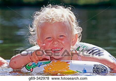 Stock Photo - Happy two year old girl takes a dip in a small lake. V? sterbotten, Sweden. Fotosearch