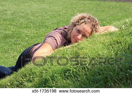 Happy woman lying on the lawn alone View Large Photo Image Stock Photo - Happy woman lying on the lawn alone. Fotosearch