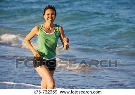 Stock Photo - Happy woman running at beach. Fotosearch