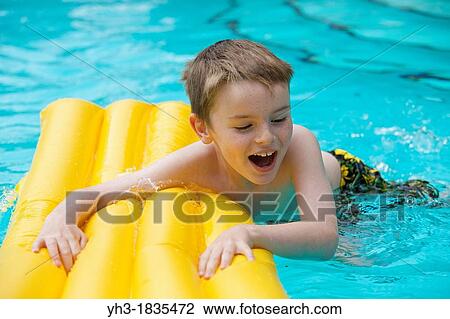 Happy young boy relaxing at the swimming pool on a yellow lilo View Large Photo Image Stock Image - Happy young boy relaxing at the swimming pool on a yellow lilo. Fotosearch