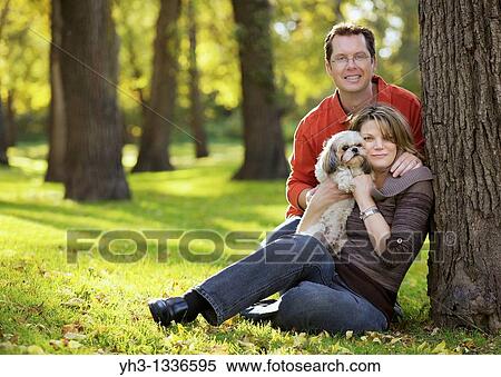 Happy young couple holding a Shih Tzu dog outdoor View Large Photo Image Stock Photography - Happy young couple holding a Shih Tzu dog outdoor. Fotosearch