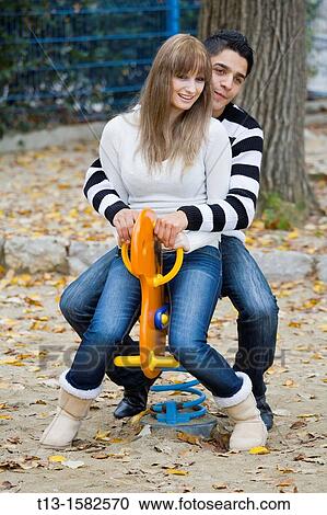 Happy young couple is riding together a rocking toy-horse View Large Photo Image Stock Image - Happy young couple is riding together a rocking toy-horse. Fotosearch