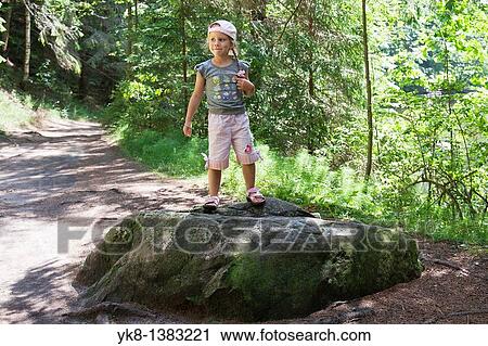 Stock Image - Happy Young Girl Standing on Stone in Forest, P? lva County, Estonia, Europe. Fotosearch