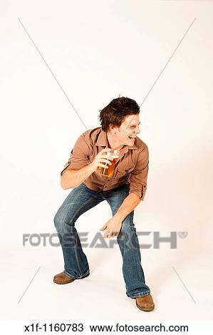 Stock Image - Happy young man drinking a pint of beer lager. Fotosearch