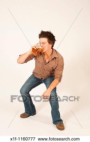 Stock Photo - Happy young man drinking a pint of beer lager. Fotosearch