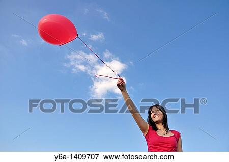 Happy young woman holding red balloon View Large Photo Image Stock Photo - Happy young woman holding red balloon. Fotosearch