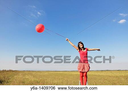 Happy young woman holding red balloon View Large Photo Image Stock Photograph - Happy young woman holding red balloon. Fotosearch