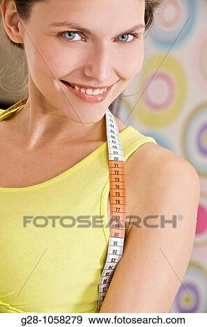happy young woman in a yellow top, with a measuring tape around her neck View Large Photo Image Stock Photo - happy young woman in a yellow top, with a measuring tape around her neck. Fotosearch