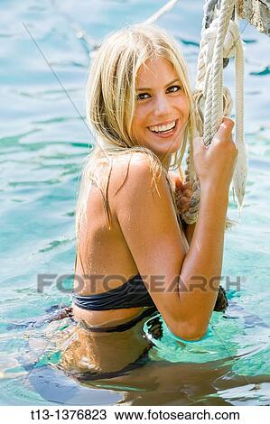 Happy young woman in water is holding a rope View Large Photo Image Stock Image - Happy young woman in water is holding a rope. Fotosearch