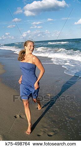 Happy young woman running on beach View Large Photo Image Picture - Happy young woman running on beach. Fotosearch
