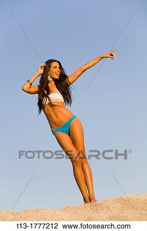 Stock Image - Happy young woman with her forefinger pointing at something. Fotosearch