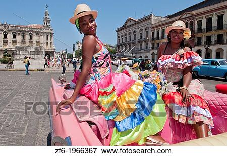 Stock Photo - Havana Cuba local women with flowers at Capital in pink Classic Ford auto and hats smiling for tourists.. Fotosearch