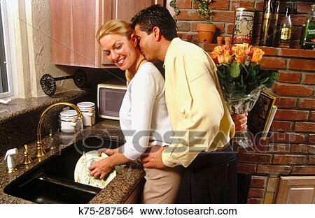 he surprises her with flowers while she's doing dishes View Large Photo Image Picture - he surprises her with flowers while she's doing dishes. Fotosearch