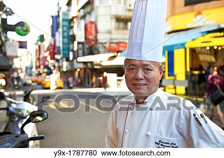 Stock Image - Head Chef Huang Lai Fa of The Grand Formosa Regent Hotel Taipei, posing and sampling food on Yongkang Street in Taipei, Taiwan. Fotosearch