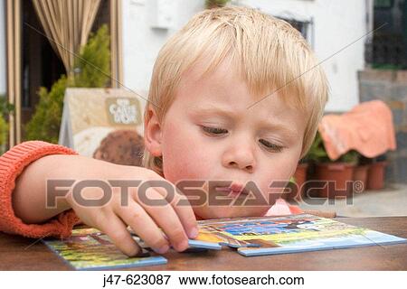 Head of a 2 year old boy as he peers over a table to do a jigsaw. View Large Photo Image Stock Photo - Head of a 2 year old boy as he peers over a table to do a jigsaw.. Fotosearch