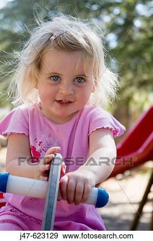 Stock Photo - Headshot, beautiful 3 year old girl outside in a park, smiling off camera. Fotosearch