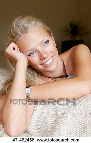 Headshot of a 21 year old girl sitting on the sofa leaning on the back looking happy View Large Photo Image Stock Photograph - Headshot of a 21 year old girl sitting on the sofa leaning on the back looking happy. Fotosearch