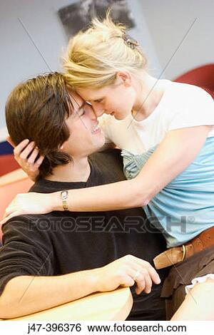 Headshot of a young couple sitting in a cafe cuddling, she? s sitting on his knee, heads and noses together View Large Photo Image Stock Photograph - Headshot of a young couple sitting in a cafe cuddling, she? s sitting on his knee, heads and noses together. Fotosearch