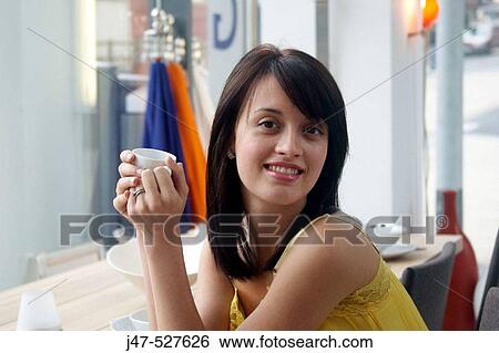 Headshot of a young girl sitting with a cup of coffee smiling into camera View Large Photo Image Stock Photograph - Headshot of a young girl sitting with a cup of coffee smiling into camera. Fotosearch