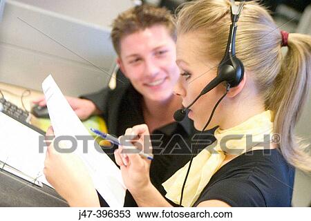 Headshot of a young man and lady at work on a computer, she's wearing headphones, selective focus on her View Large Photo Image Stock Image - Headshot of a young man and lady at work on a computer, she's wearing headphones, selective focus on her. Fotosearch