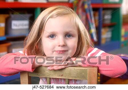 Headshot of a4 year old girl smiling into camera at nursery, with her chin resting on her hands View Large Photo Image Picture - Headshot of a4 year old girl smiling into camera at nursery, with her chin resting on her hands. Fotosearch