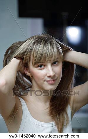 Stock Image - headshot of the pretty blond women weared tank top indoors smiling with heands in hairs Caucasian, 24 years old. Fotosearch