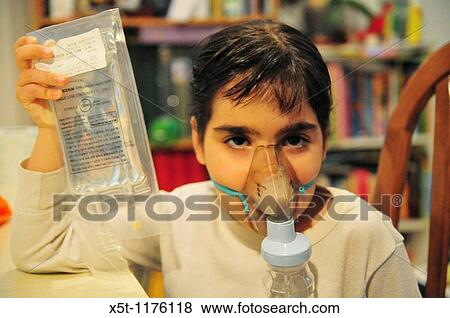 Stock Photo - Health - young girl of 8 suffers from Asthma oxygen humidifier inhaler helps her breath - Model Release available. Fotosearch