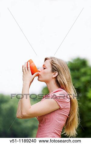 Stock Image - Healthy blonde woman enjoying a soup in the park. Fotosearch