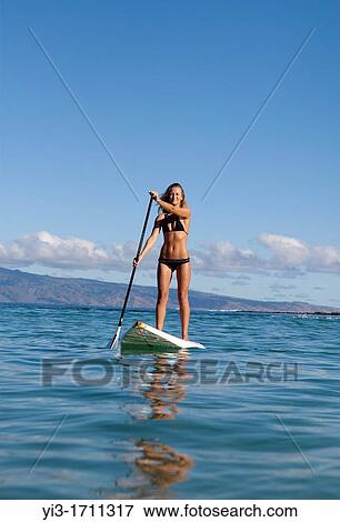 Stock Photo - Healthy woman stand up paddles at Napili Bay, Maui, Hawaii. Fotosearch