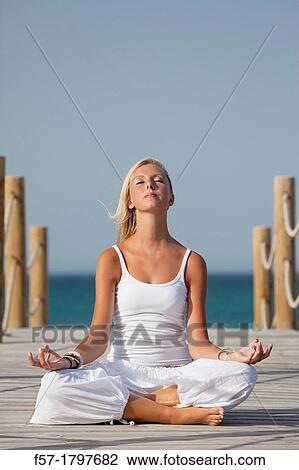 Healthy young meditating on a boardwalk View Large Photo Image Stock Image - Healthy young meditating on a boardwalk. Fotosearch