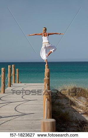 Healthy young woman balancing on a post at the beach View Large Photo Image Stock Photo - Healthy young woman balancing on a post at the beach. Fotosearch