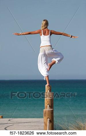 Healthy young woman balancing on a post at the beach View Large Photo Image Stock Photograph - Healthy young woman balancing on a post at the beach. Fotosearch