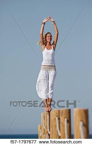 Healthy young woman balancing on a wooden post View Large Photo Image Stock Photo - Healthy young woman balancing on a wooden post. Fotosearch