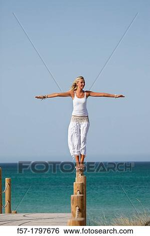 Stock Photograph - Healthy young woman balancing on a wooden post. Fotosearch