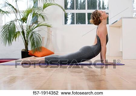 Stock Image - Healthy young woman doing the upward-facing dog yoga position. Fotosearch