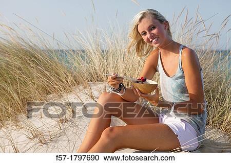 Healthy young woman eating fruit at the beach View Large Photo Image Stock Image - Healthy young woman eating fruit at the beach. Fotosearch