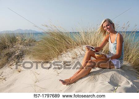 Healthy young woman eating fruit at the beach View Large Photo Image Stock Photo - Healthy young woman eating fruit at the beach. Fotosearch