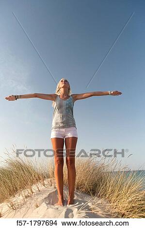 Picture - Healthy young woman in the dunes exercising. Fotosearch