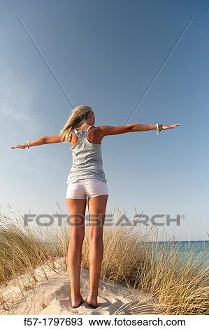 Stock Image - Healthy young woman in the dunes exercising. Fotosearch