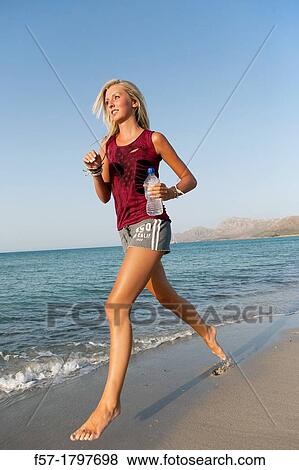 Stock Photo - Healthy young woman jogging on the beach. Fotosearch